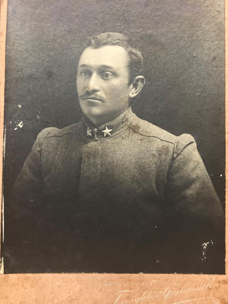 Indossa una uniforme grigio-verde con due stelle di metallo sul colletto.   